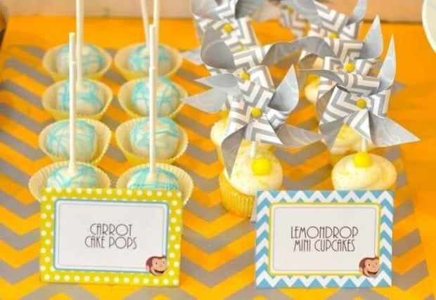 Curious George party foods, including lemon and carrot cake pops, bedecked this dessert table.
