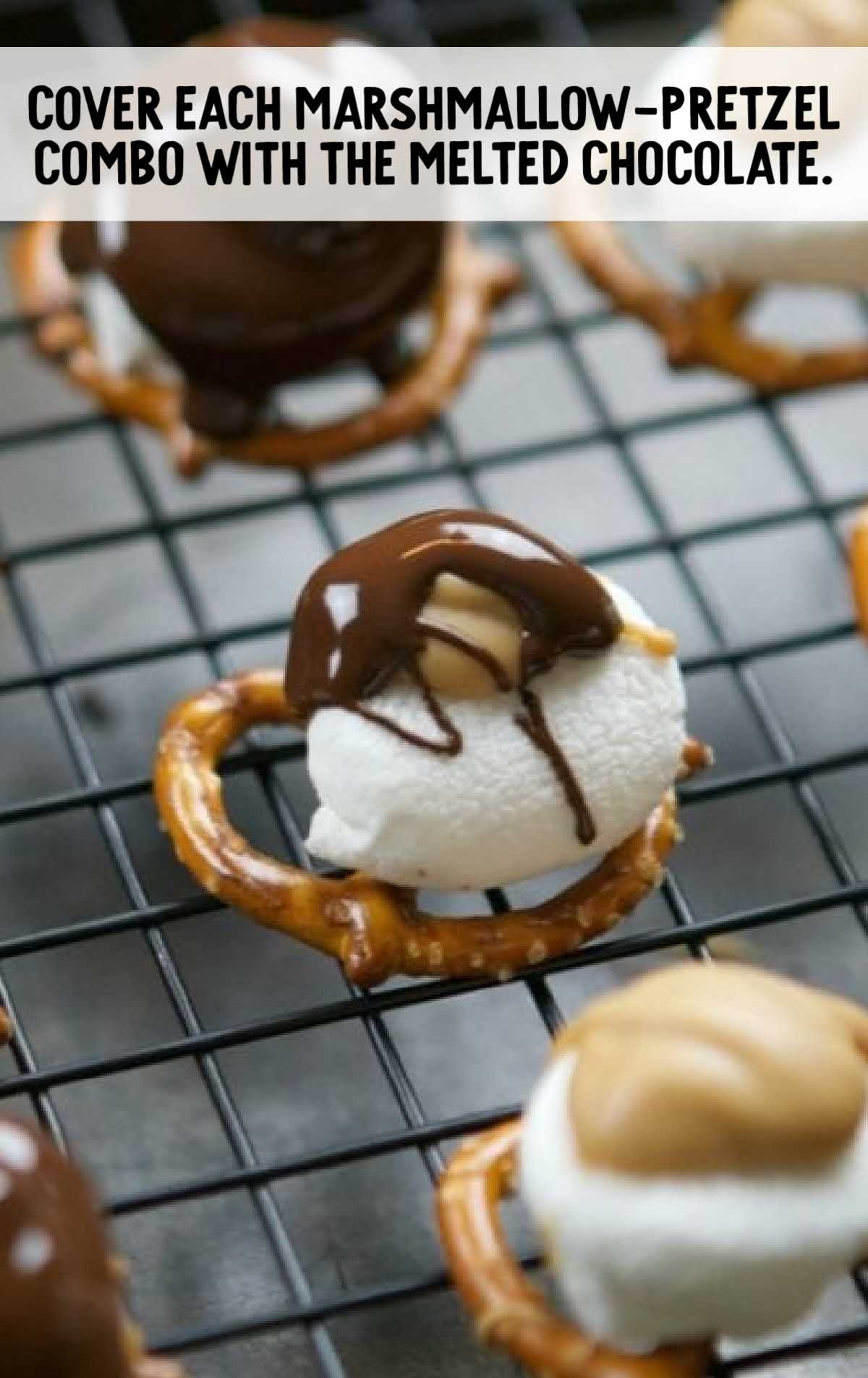 Marshmallow and peanut butter-topped pretzels being covered with melted chocolate on a wire rack.