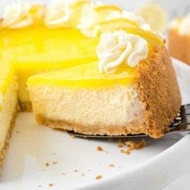 close up shot of lemon cheesecake with a slice being removed with a spatula
