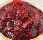 A close up of food on a plate, with Cranberry and Sauce