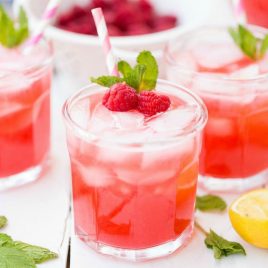 A close up of a glass of orange juice, with Lemonade and Raspberry