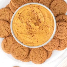 close up overhead shot of a bowl of Pumpkin Dip topped with cinnamon around a bunch of cookies