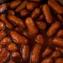 close up shot of Instant Pot Little Smokies in a instant pot with a wooden spoon