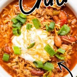 close up overhead shot of a bowl of Turkey Chili topped with sour cream and cheddar cheese then garnished with green onions