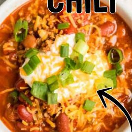 close up overhead shot of a bowl of Turkey Chili topped with sour cream and cheddar cheese then garnished with green onions