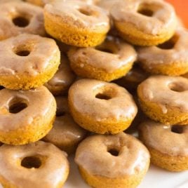 close up shot of pumpkin donuts stacked on top of each other on a plate