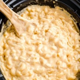 close up shot of Crockpot Mac and Cheese in a crockpot with a large wooden spoon