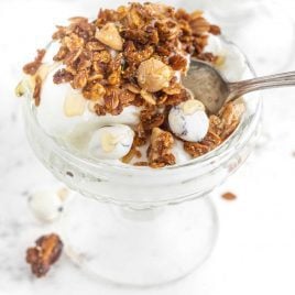 close up shot of apple cinnamon granola served over yogurt in a cup