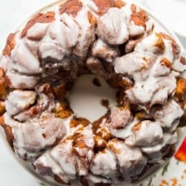 Top-down view of cinnamon roll monkey bread ring glazed with icing on a cake stand