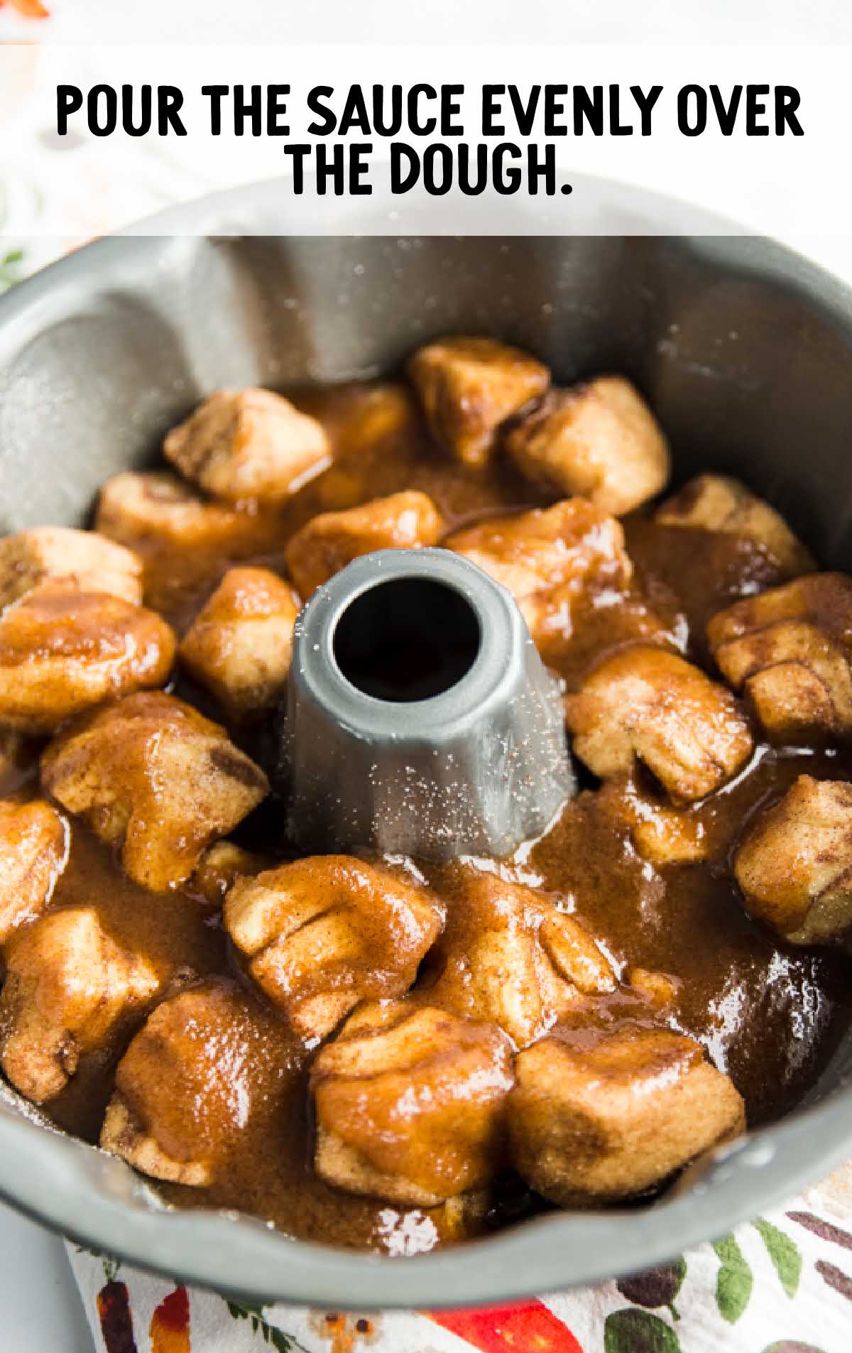 Baking pan filled with cinnamon roll dough pieces and sauce poured evenly over the top