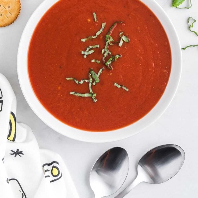 close up overhead shot of a bowl of homemade tomato soup recipe topped with basil