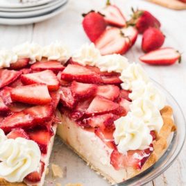 strawberry cream cheese pie with sliced strawberries and a whipped topping in a clear pie dish