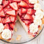 close up overhead shot of strawberry cream cheese pie with sliced strawberries and a whipped topping in a clear pie dish