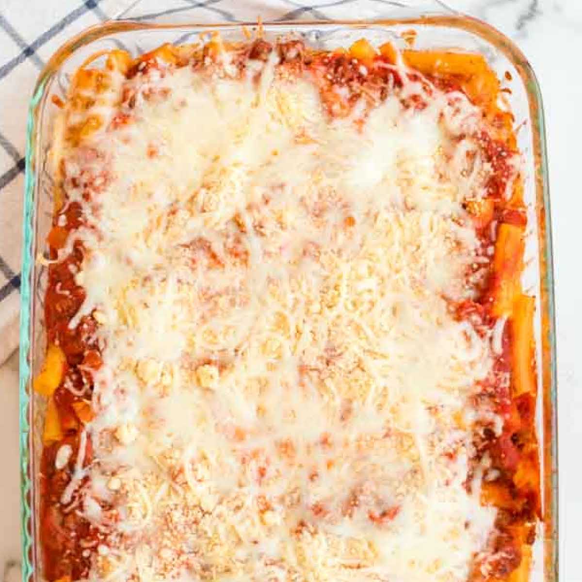 overhead shot of a baking dish of baked ziti topped with cheese