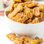 close up shot of Pumpkin Dog Treats drizzled with peanut butter and piled in a bowl