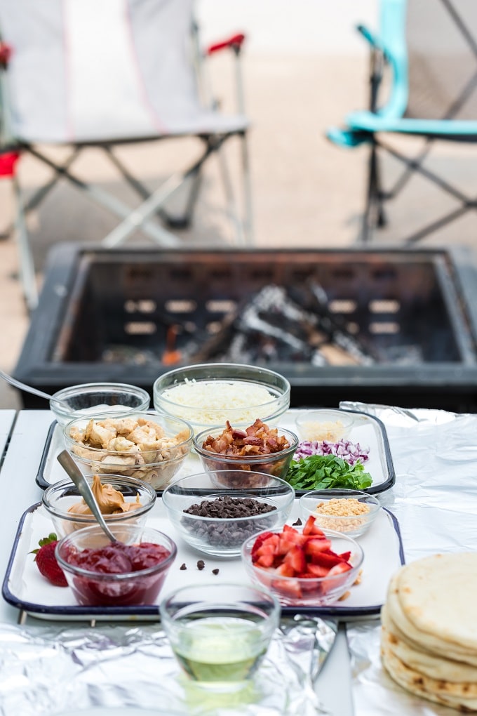 Une table garnie d'assiettes de nourriture sur une assiette, avec Pizza et Feu de camp