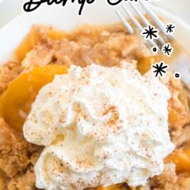 close up overhead shot of a serving of peach dump cake topped with whipped cream