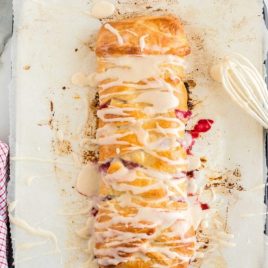 overhead shot of Cherry Breakfast Braid drizzled with glaze on a baking dish