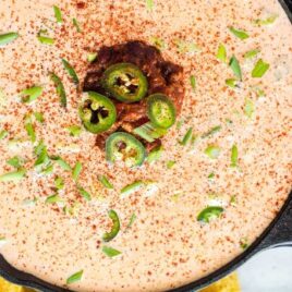 close up overhead shot of a bowl of Chili Cheese Dip topped with green onions and jalapeños