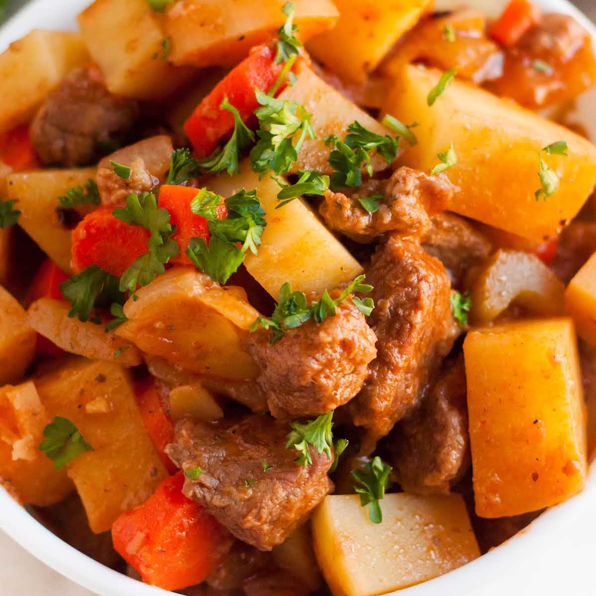close up shot of a bowl of beef stew garnished with parsley