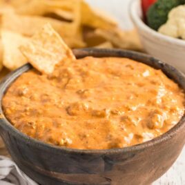 a bowl of Chili Cheese Dip with a tortilla chip