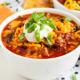 close up shot of Instant Pot Chili topped with sour cream and green onions in a bowl