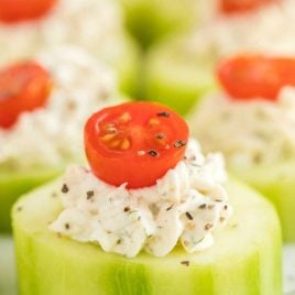 close up shot of Cucumber Bites topped with cream cheese and a slice of grape tomato