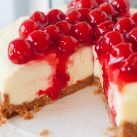 A close up of a slice of cake on a paper plate, with Cheesecake