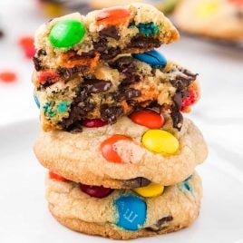 close up shot of a plate of m&m cookies stacked on top of each other