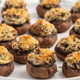 a bunch of Stuffed Mushrooms garnished with parsley on a plate