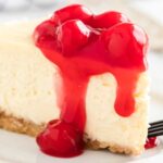 close up shot of a slice of Cheesecake topped with a cherry glaze on a plate