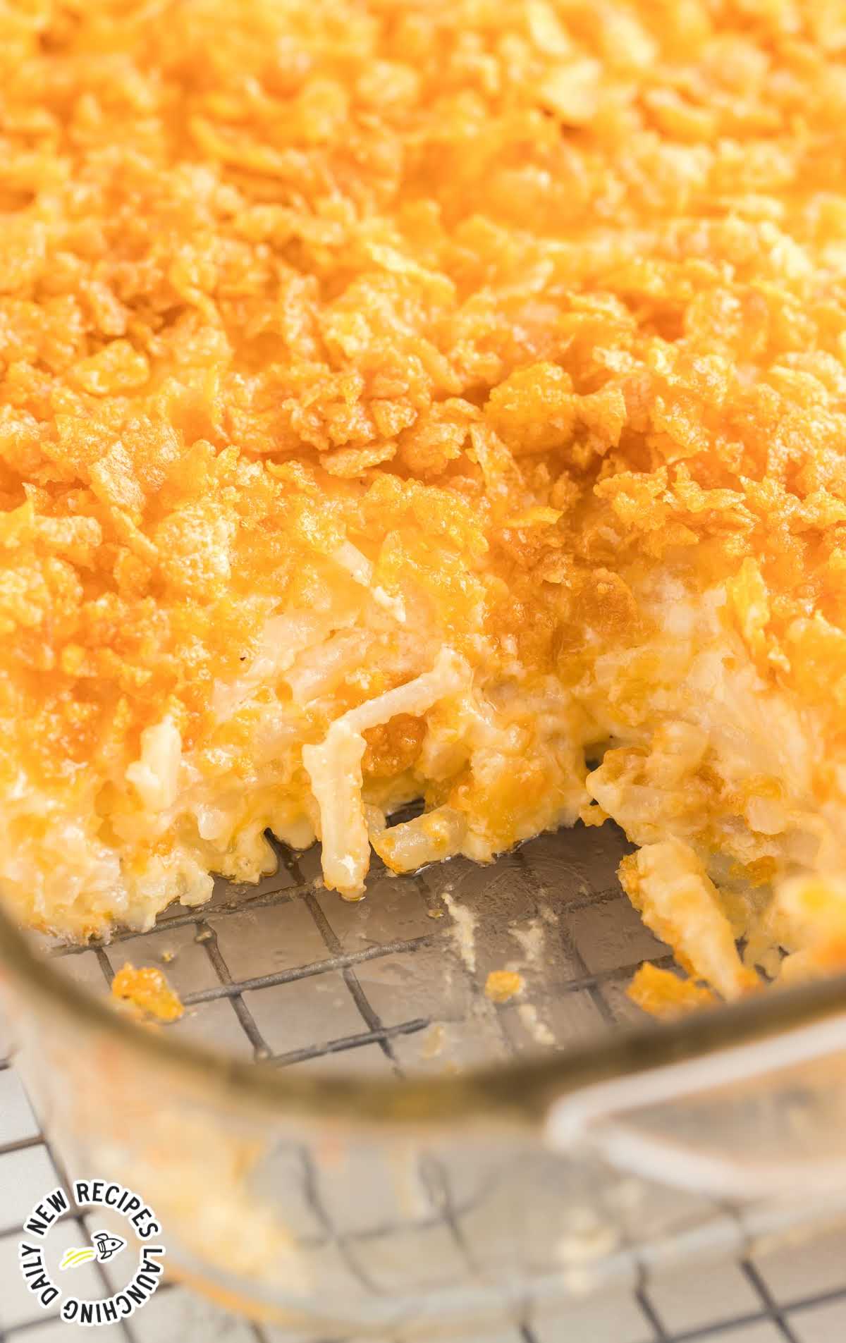 close up shot of Cheesy Potato Casserole in a baking dish with a serving taken out of it