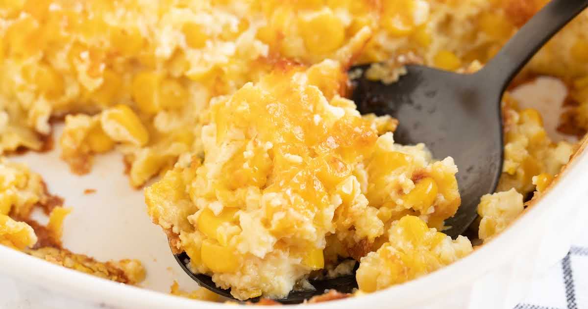 close up shot of a serving of Corn Pudding being picked up from the dish with a large spoon