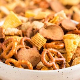 close up shot of a bowl of Crockpot Chex Mix surrounded by Crockpot Chex Mix