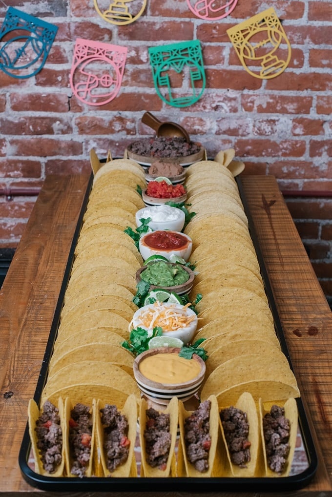 A tray of food on a wooden table, with Taco Bar