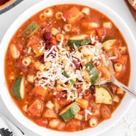 close up overhead shot of a bowl of Minestrone Soup topped with parmesan cheese and served with a spoon