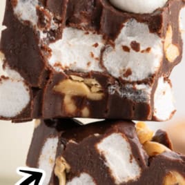 Two thick squares of Rocky Road Fudge are stacked, revealing chunks of marshmallows and nuts nestled inside rich chocolate. Text reads Rocky Road Fudge Recipe and Vintage Recipe! in bold fonts with decorative accents.