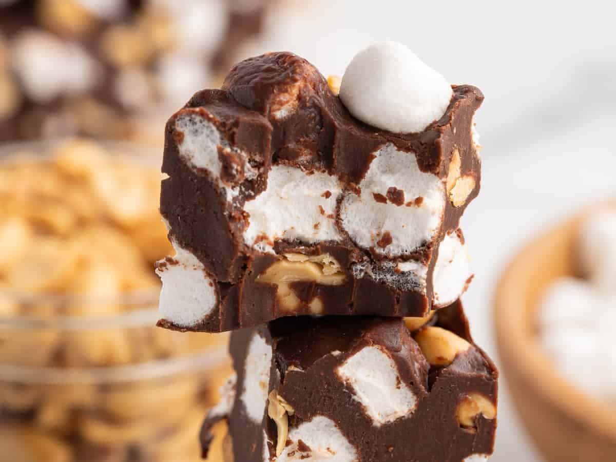 Two stacked pieces of Rocky Road Fudge with visible marshmallows and peanuts, showing a rich, chocolatey texture and a bite taken from the top piece—a tempting treat that perfectly showcases this classic Rocky Road Fudge Recipe.
