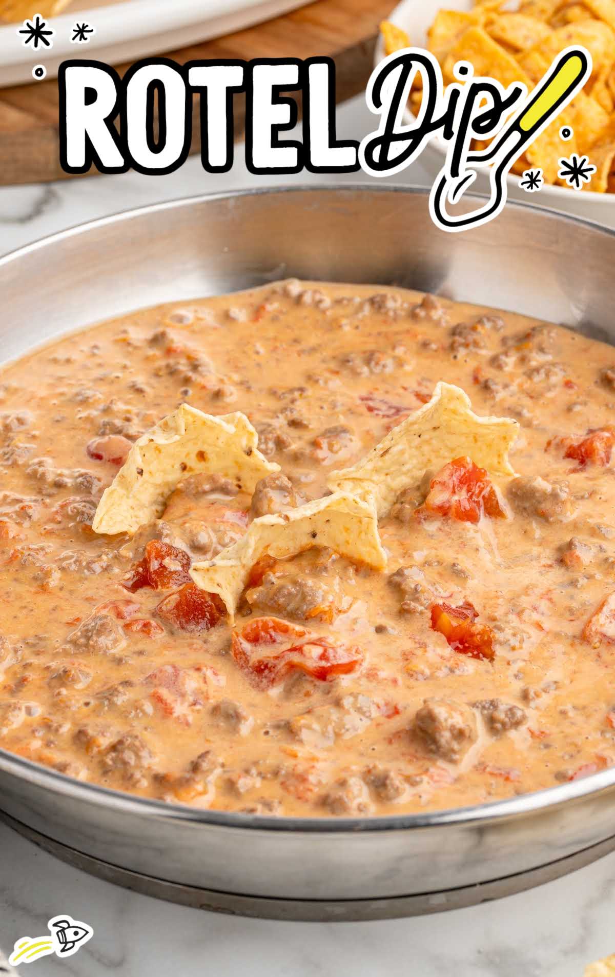 Rotel dip in a skillet with star-shaped tortilla chips dipped into the cheesy mixture.