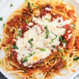 close up of chicken parmesan served over spaghetti