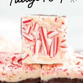 A close up shot of Layered Peppermint Fudge stacked on top of each other on wooden board