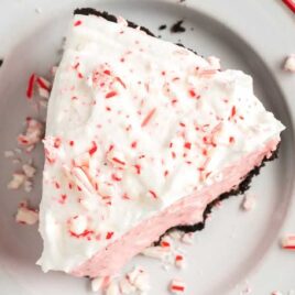 close up overhead shot of a slice of candy cane pie garnished with crushed candy canes on a plate