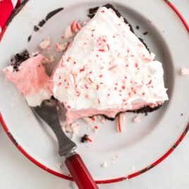 close up overhead shot of a slice of candy cane pie garnished with crushed candy canes on a plate
