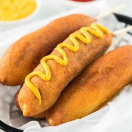 A plate with a hot dog on a bun, with Corn dog