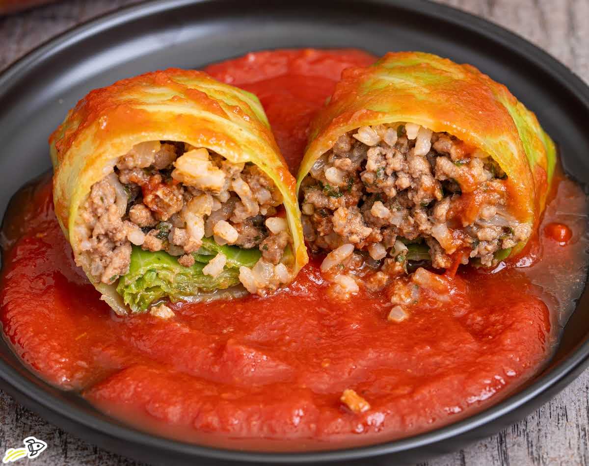 close-up cabbage roll cut in half showing ground beef rice filling in tomato sauce