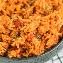 A close up of a bowl of food with rice meat and vegetables, with Spanish rice