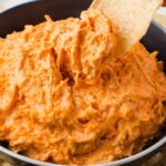 close up shot of a bowl of Crockpot Buffalo Chicken Dip with a tortilla dipped into it