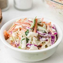 classic coleslaw topped with homemade salad dressing in a white bowl