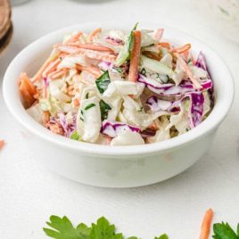 classic coleslaw topped with homemade salad dressing in a white bowl