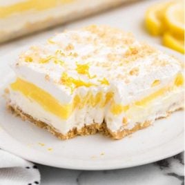 close up shot of a slice of lemon lasagna with a piece taken out of it on a plate